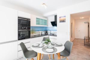een keuken en eetkamer met een witte tafel en stoelen bij Apartment "Haffblick" - Haffresidenz in Zirchow