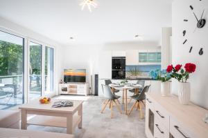 een woonkamer met een tafel en stoelen en een keuken bij Apartment "Haffblick" - Haffresidenz in Zirchow