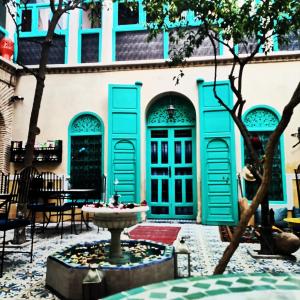 a building with blue doors and a fountain in a courtyard at Riad Al Nour in Marrakech