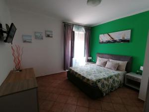 - une chambre avec des murs verts et un lit dans un dortoir dans l'établissement B&B Il Corallo, à La Maddalena