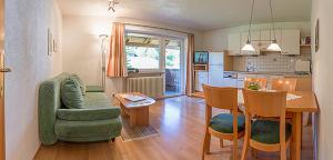 ein Wohnzimmer und eine Küche mit einem grünen Sofa und einem Tisch in der Unterkunft Gruggerhof in Seefeld in Tirol
