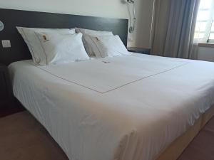 ein großes weißes Bett mit weißer Bettwäsche und Kissen in der Unterkunft Hotel Vila Luena in Vila Verde