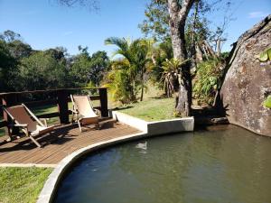 a wooden deck with two chairs and a pool of water at Hospedaria Vida na Roça in São Bento do Sapucaí
