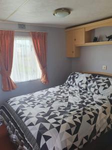 1 dormitorio con 1 cama en blanco y negro y ventana en 64 Southfield - Skipsea Sands en Ulrome