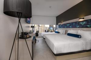 River Garden Hotel + Suites في غواياكيل: غرفه فندقيه سريرين ومصباح