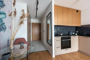 kuchnia z białymi szafkami i szklanym stołem w obiekcie apartamenty-wroc Kurkowa we Wrocławiu