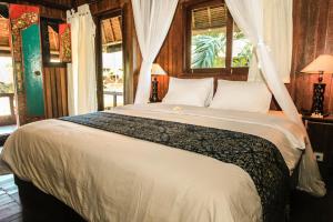 ein Schlafzimmer mit einem großen weißen Bett mit einem Fenster in der Unterkunft Radiant Jepun Villa in Legian