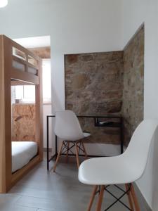 a bedroom with two white chairs and a bunk bed at Hostel Sertã in Sertã