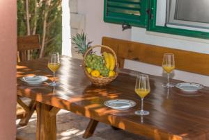 a wooden table with a basket of fruit and wine glasses at Holiday home Frane in Slivno