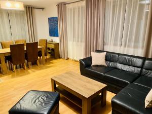 a living room with a black leather couch and a table at RIVIERA LIPNO 502 Apartmán 4kk u vody in Lipno nad Vltavou
