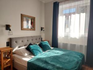 a bedroom with a bed with blue pillows and a window at 4 STRONY ŚWIATA Pokoje i Apartamenty in Dźwirzyno