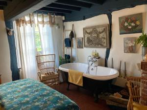 a bathroom with a bath tub and a bed at La Ferme du Val de Lys in Nolléval