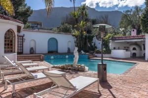 a house with a swimming pool with chairs and a statue at Anoud Manor in Hout Bay
