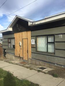 ein Haus mit einer Holztür neben einem Bürgersteig in der Unterkunft Xalpen B&B in Puerto Natales