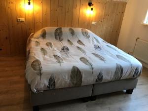 Una cama con una manta con plumas. en Kom in de Bedstee Magie!, en Winterswijk