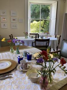 einen Esstisch mit Tellern und Blumen darauf in der Unterkunft Grange Farm in Thetford