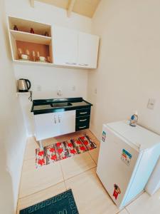 a small kitchen with a white refrigerator in a room at Pousada Paredão dos Canyons in Praia Grande