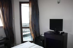 a bedroom with a bed and a television and a window at Saint Sofia Guest House Къща за Гости in Nesebar