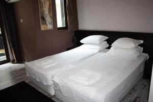 two beds in a room with white sheets and pillows at Saint Sofia Guest House Къща за Гости in Nesebar