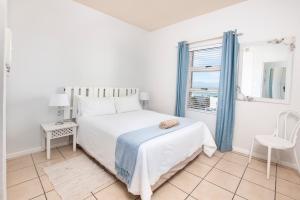 a white bedroom with a bed and a window at La Palma Villas 35 in Mossel Bay