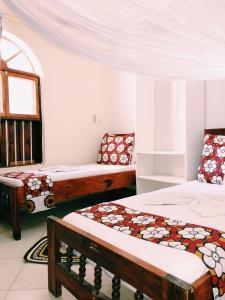 ザンジバルシティにあるKelele Squareのベッド3台と窓が備わる客室です。