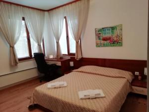 um quarto com 2 camas, uma secretária e janelas em Къща в центъра на Стрелча, джакузи с минерална вода em Strelcha