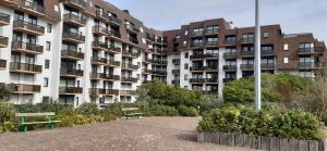 un edificio de apartamentos con dos bancos delante en Koksijde Promenade, en Koksijde