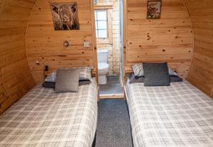 a bedroom with two beds in a cabin with a toilet at The Shielings by Inverlochy Villas in Fort William