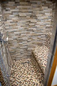 einen Stuhl in einem Zimmer mit einer gefliesten Wand in der Unterkunft Steamy Cottage a cosy couples cottage & steam room in Haworth