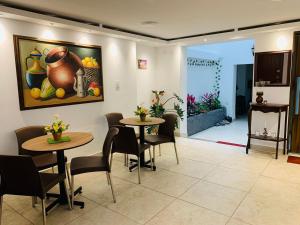 two tables and chairs in a room with a painting on the wall at Hostel Casa Zambrano in Popayan