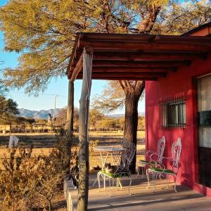 a red building with chairs and a table and a tree at Cabañas Los Algarrobos in San Marcos Sierras