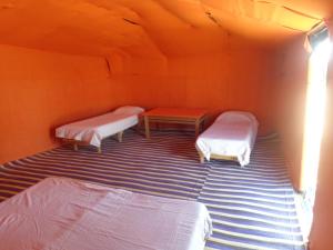 
two beds in a small room with wooden floors at Camel Trek Bivouac in Merzouga
