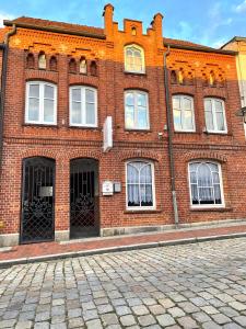 a red brick building with white windows on a street at Just Bar - Pension in Gadebusch