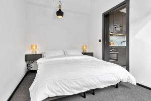 a white bedroom with a large bed with white sheets at In the heart of Narvik ! in Narvik