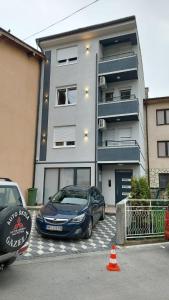 two cars parked in a parking lot in front of a building at Demir Apartmani in Novi Pazar