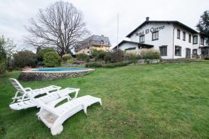Duas espreguiçadeiras brancas e uma piscina num quintal em Hotel El Ciervo em Villarrica