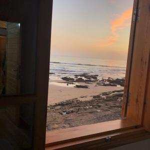 een raam met uitzicht op het strand bij beachfront house in Taghazout