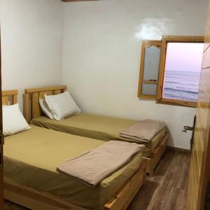 two beds in a room with a window at beachfront house in Taghazout