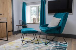 uma sala de estar com uma cadeira azul e uma televisão em The Hideaway em Great Massingham