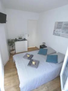 a white bedroom with a large bed with blue pillows at Le Capitaine Jack in Trouville-sur-Mer