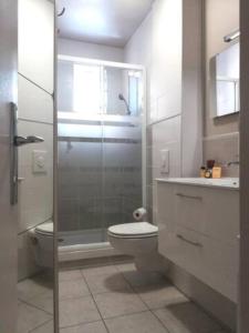 a bathroom with a toilet and a glass shower at Le Capitaine Jack in Trouville-sur-Mer