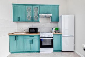 a kitchen with blue cabinets and a white refrigerator at RAISSON APARTHOTEL H252 Хан Шатыр in Taldykolʼ +8 photos