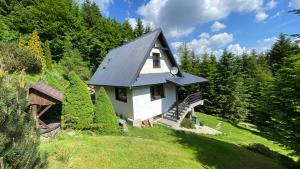 a small white house on a hill with trees at Mountain Cottage Lubomierz in Lubomierz