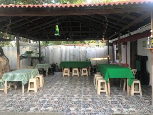 un patio con mesas verdes y sillas bajo toldo en Cabaña La Fortaleza en Tolú
