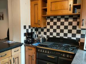 a kitchen with a black stove and a checkered wall at La Maison de Valy in Montreuil-sur-Mer