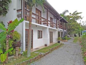 a white building with a palm tree next to a street at Recanto da Madre in Guarda do Embaú +21 photos