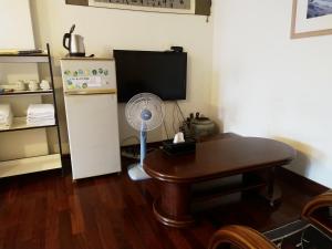 a room with a table and a refrigerator and a fan at Taitung Travel Hostel in Taitung City