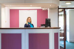 a woman standing behind a counter with a computer at The Derwentwater Hotel in Keswick