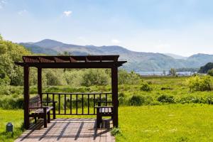 a wooden bench sitting on top of a lush green field at The Derwentwater Hotel in Keswick