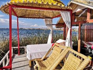- une terrasse couverte avec une table, des chaises et l'eau dans l'établissement Uros Qhota Uta Lodge, à Puno